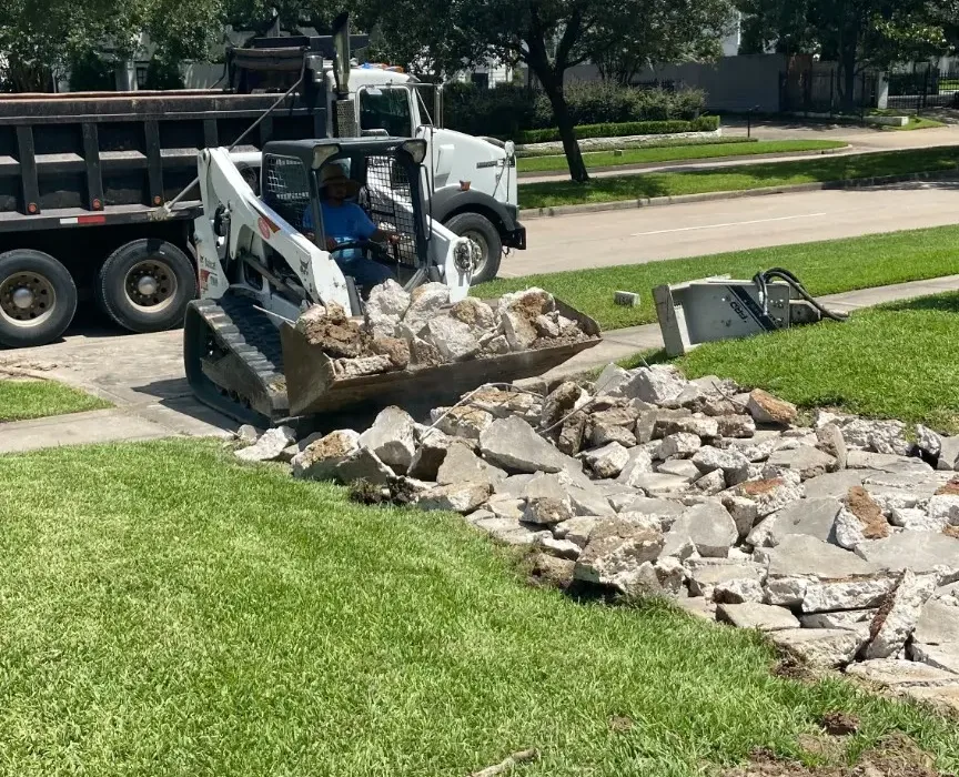 Removed concrete debris being cleared from the residential driveway entrance